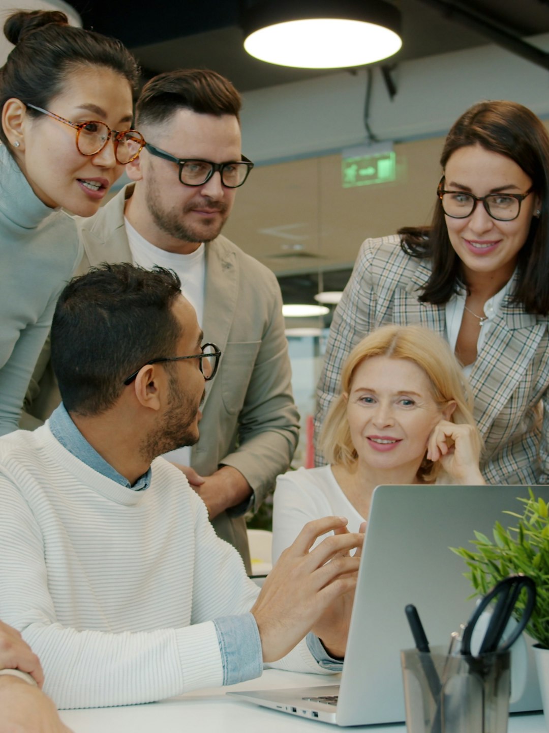 Diverse client and consulting team working together around one laptop